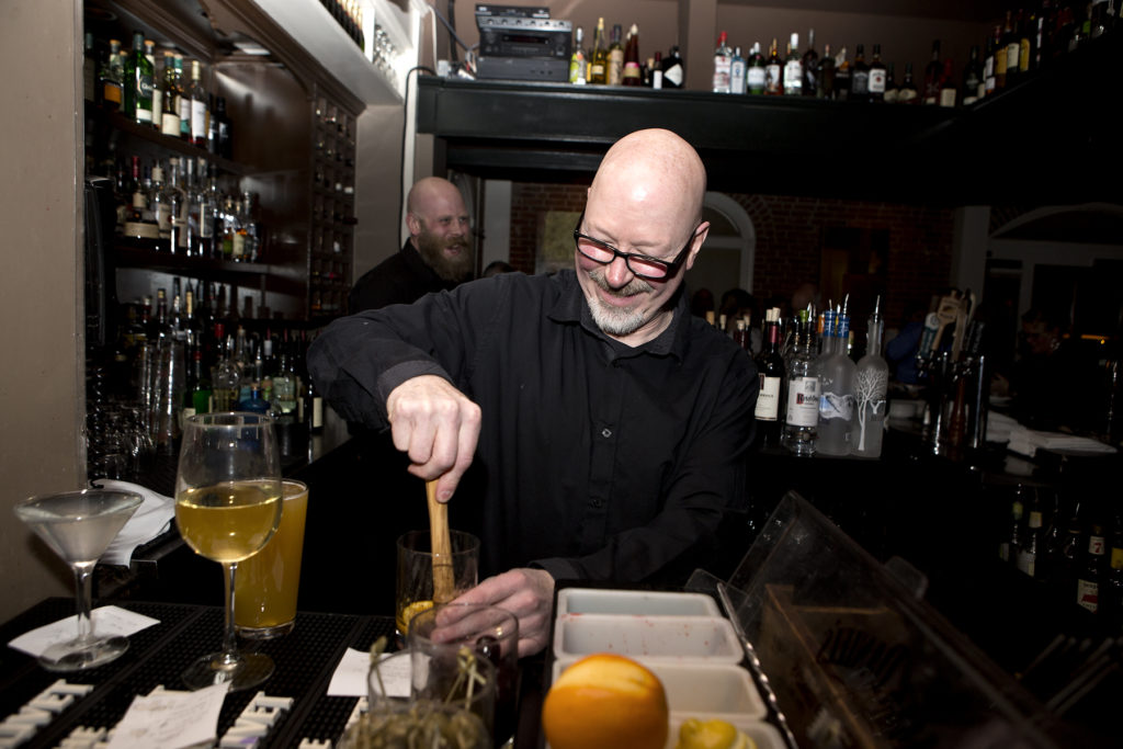 Smiling bartender muddling a drink